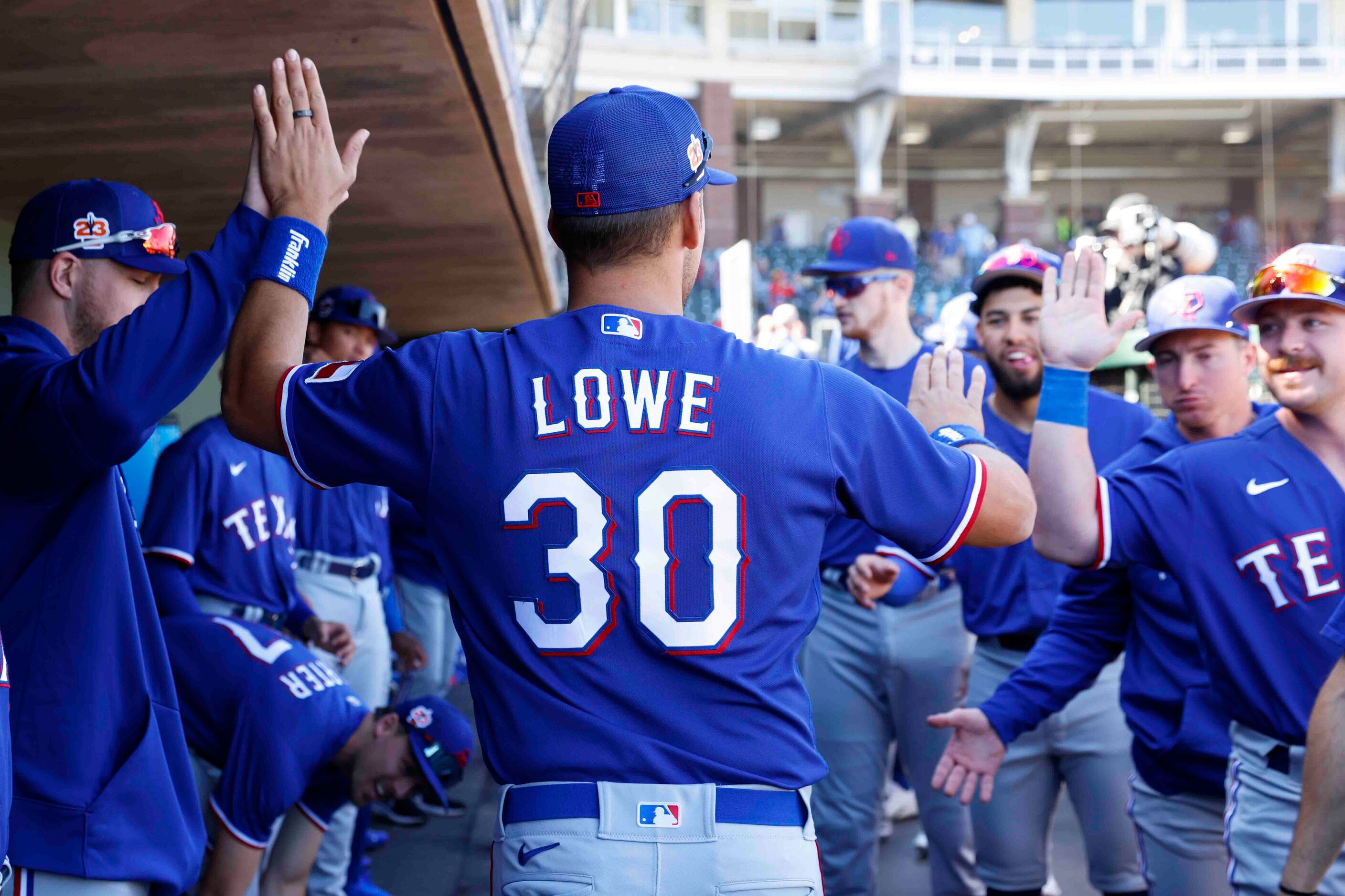 Texas Rangers Nathaniel Lowe high-fives players being introduced during a spring training...