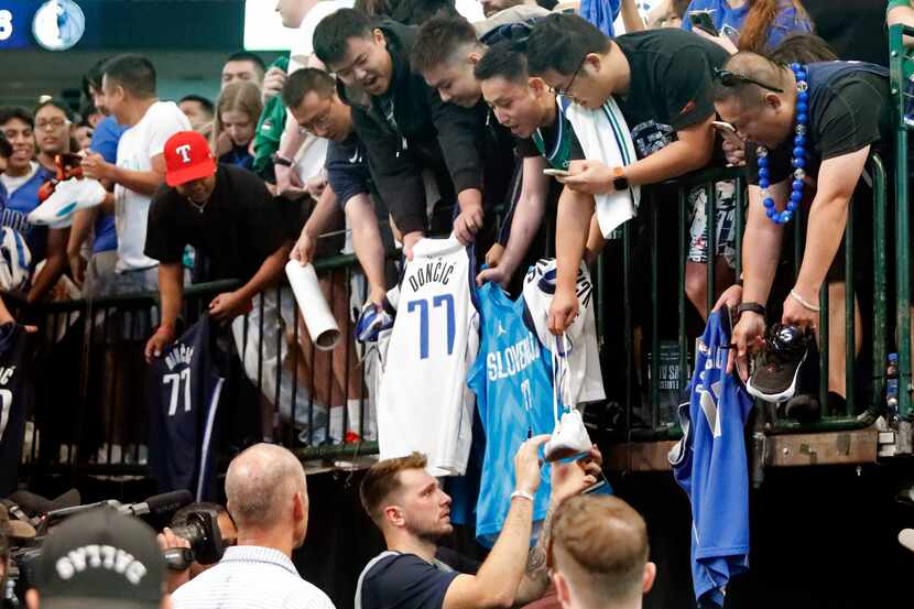 Dallas Mavericks guard Luka Doncic (77) prepares to autograph a shoe after the game at the...