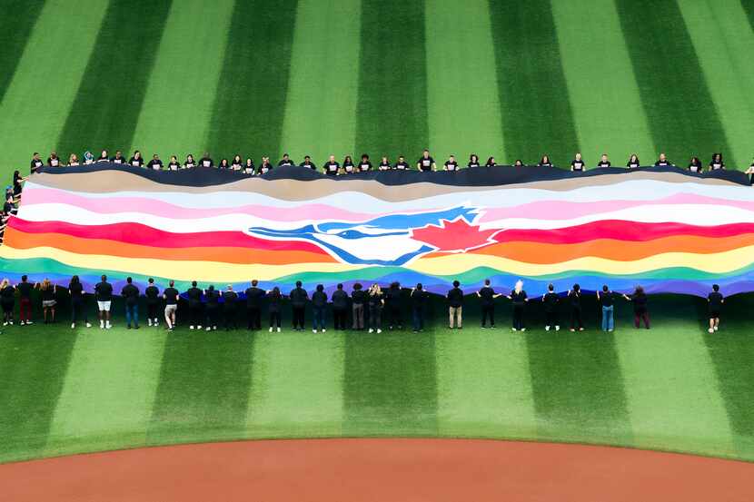 Un grupo de personas sostiene una bandera de los Azulejos de Toronto para festejar el Fin de...