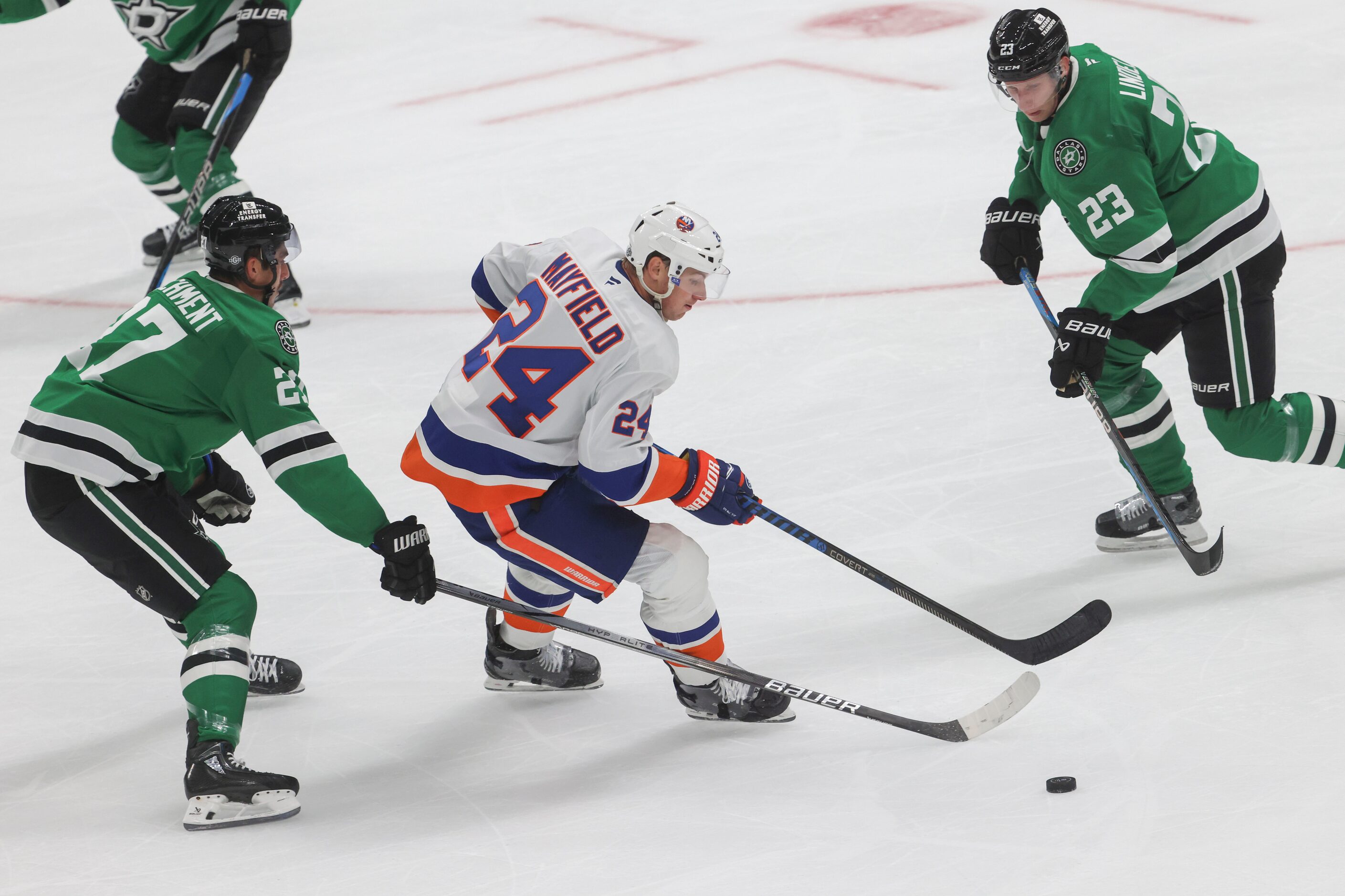 New York Islanders defenseman Scott Mayfield (center) controls the puck against Dallas Stars...