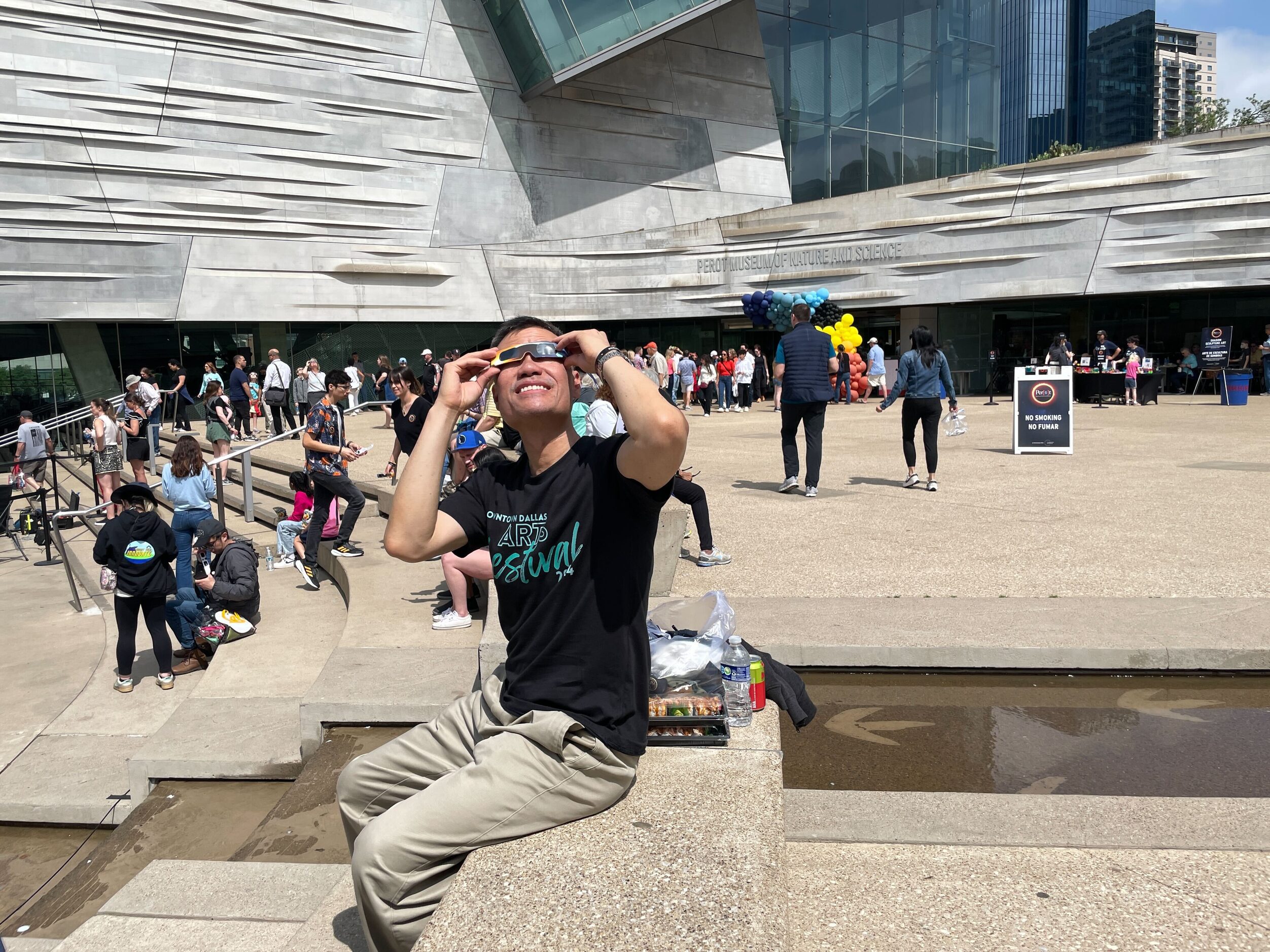 Andrew C. of Los Angeles uses his solar eclipse glasses to look up as the sun breaks through...