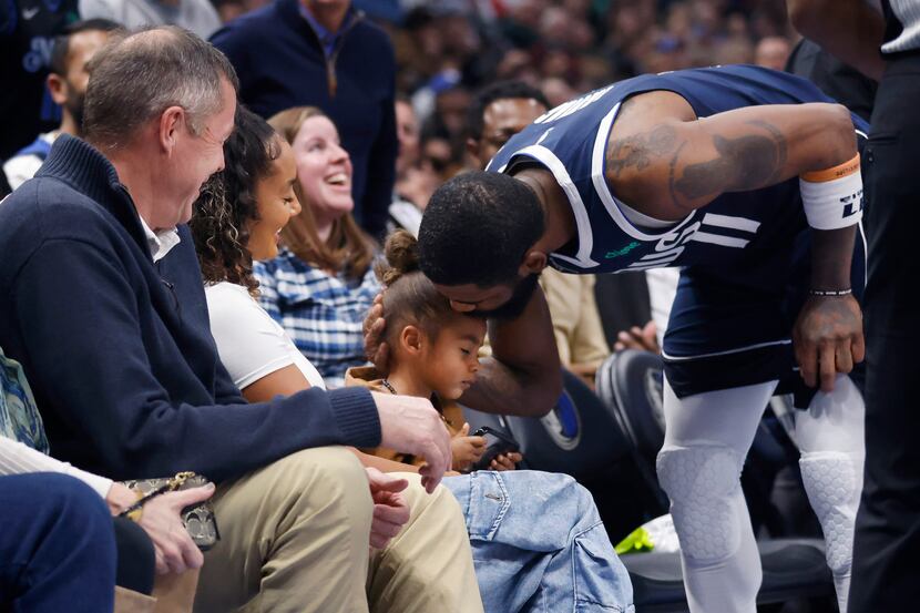 Dallas Mavericks guard Kyrie Irving (11) gives his son a kiss on the bench after Washington...