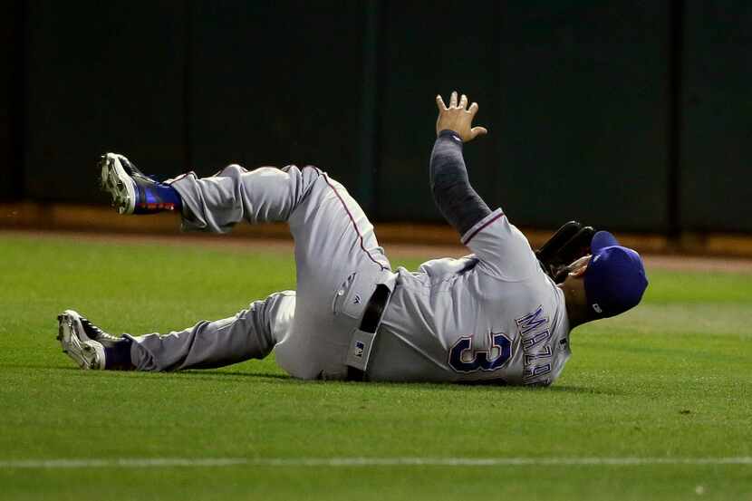 Texas Rangers right fielder Nomar Mazara goes tumbling after losing control of a ground ball...