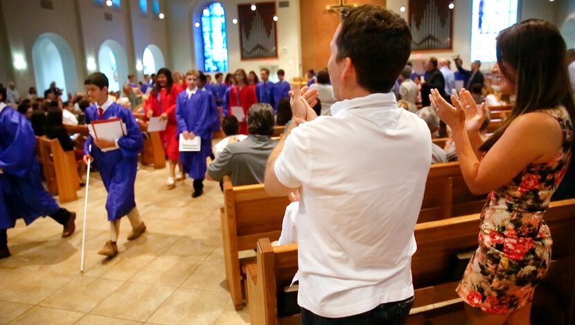 Joey and Johanna Uek applaud their son Zach (left) as he and his class exit their graduation...