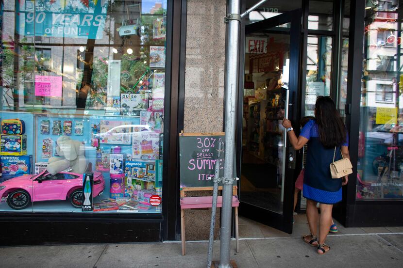 Discount posters are shown in the window of Mary Arnold Toys in New York on August 2.