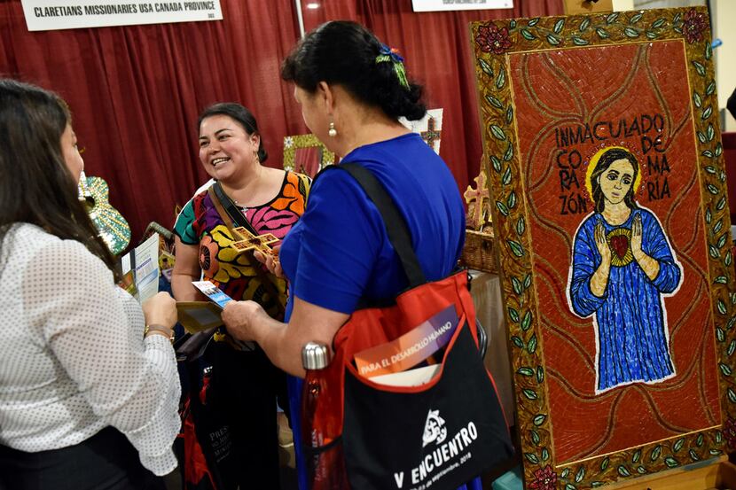 Olivia Rubio, left, of Fort Worth, meets with friends at a booth shopping for religious art...