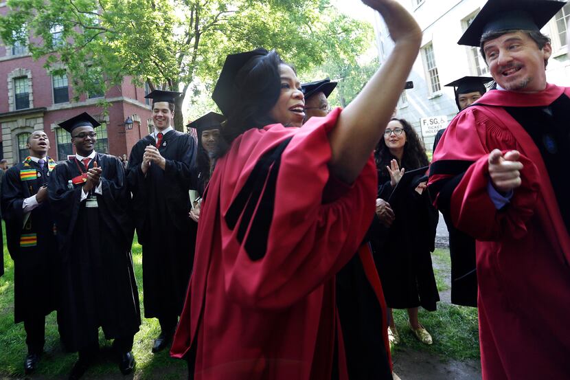Oprah Winfrey holds her hand up to high-five graduates as she walks during the procession at...