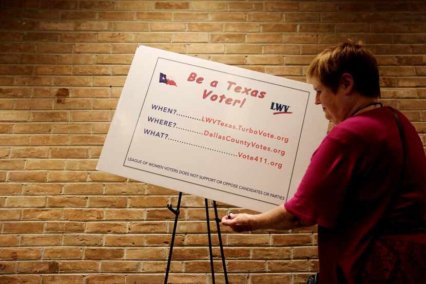 Elizabeth Walley of Mesquite, part of the League of Women Voters, hung a poster before a...