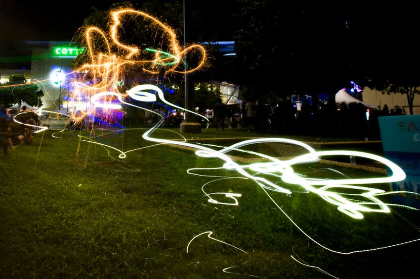 A celebrant twirling with a sparkler leaves a trail in a long exposure photograph near the...