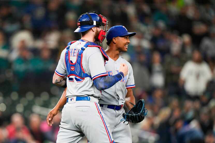 Texas Rangers catcher Jonah Heim, left, celebrates clinching a playoff spot in the American...