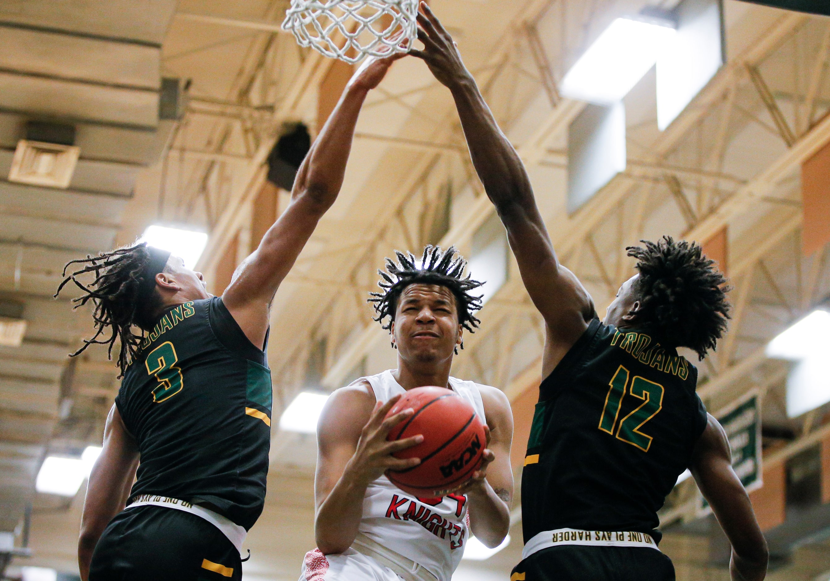 Kimball junior Corey Flowers, center, attempts a layup as Newman Smith seniors Jarren Cook...