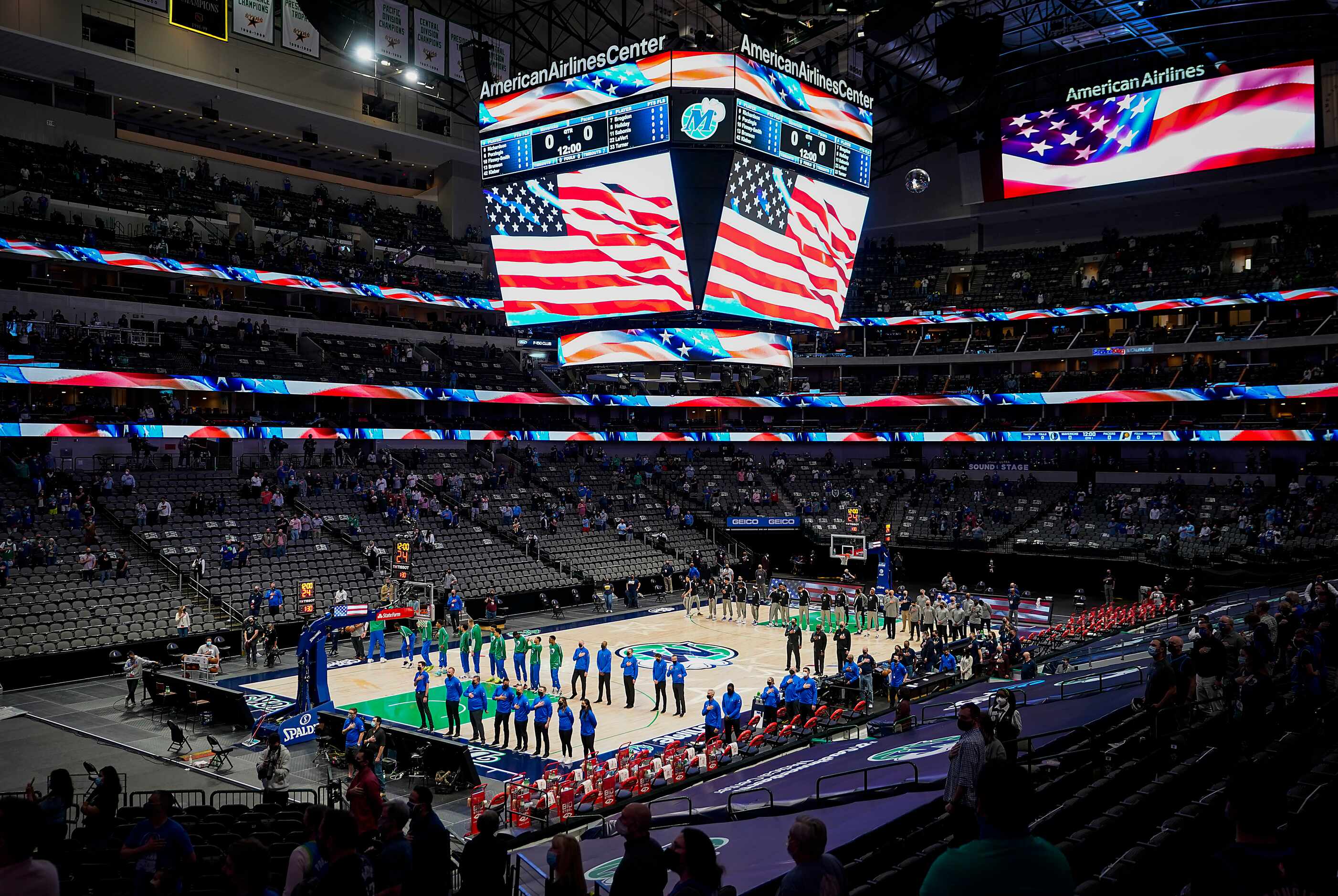 Dallas Mavericks players and staff stand for the national anthem before an NBA basketball...
