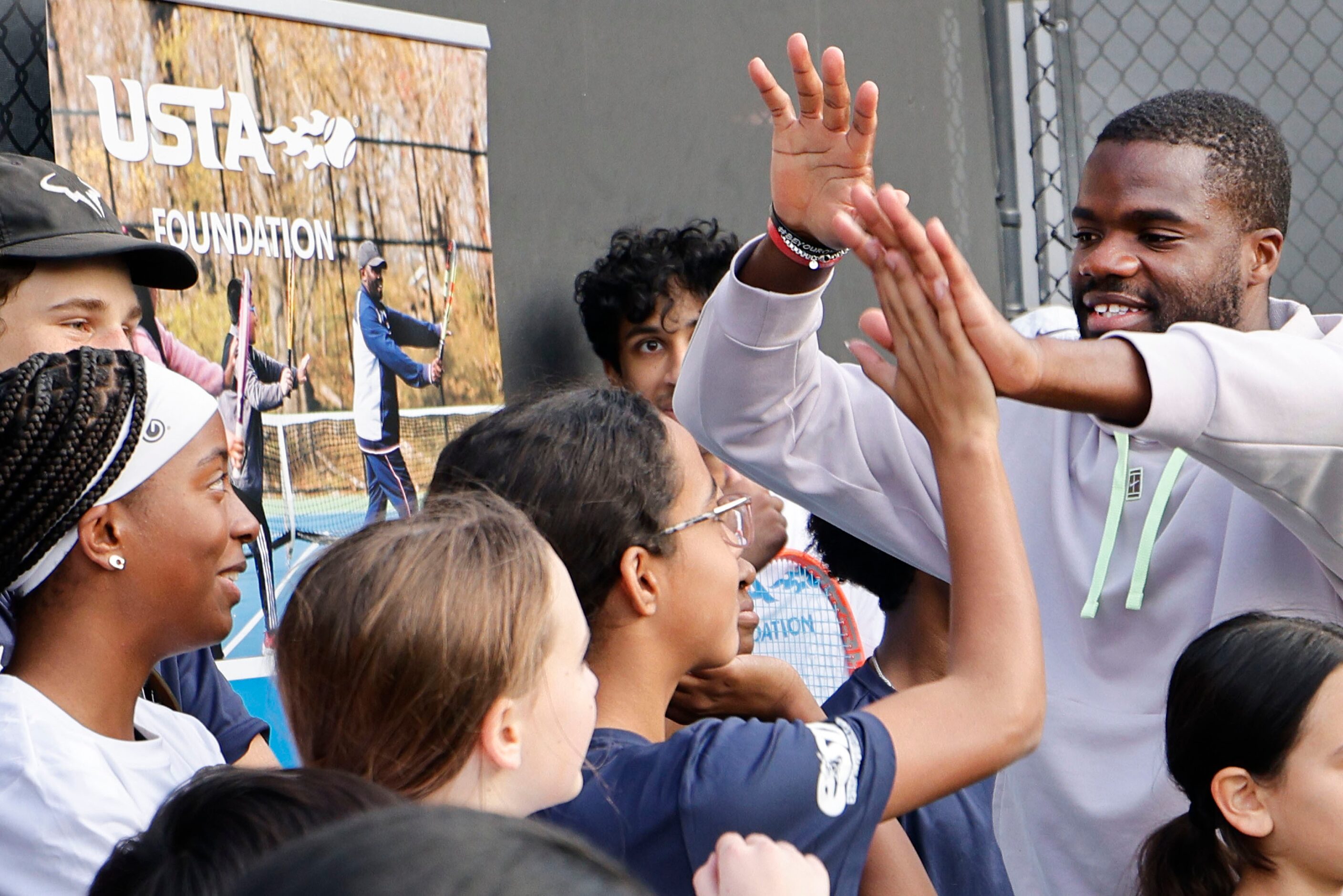 American tennis star Frances Tiafoe, right, high-fives students from Dallas Tennis Education...