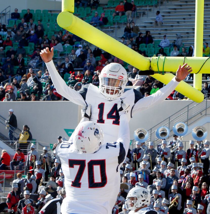 Allen quarterback Grant Tisdale (14) is hoisted in the end zone by teammate Trey Stratford...