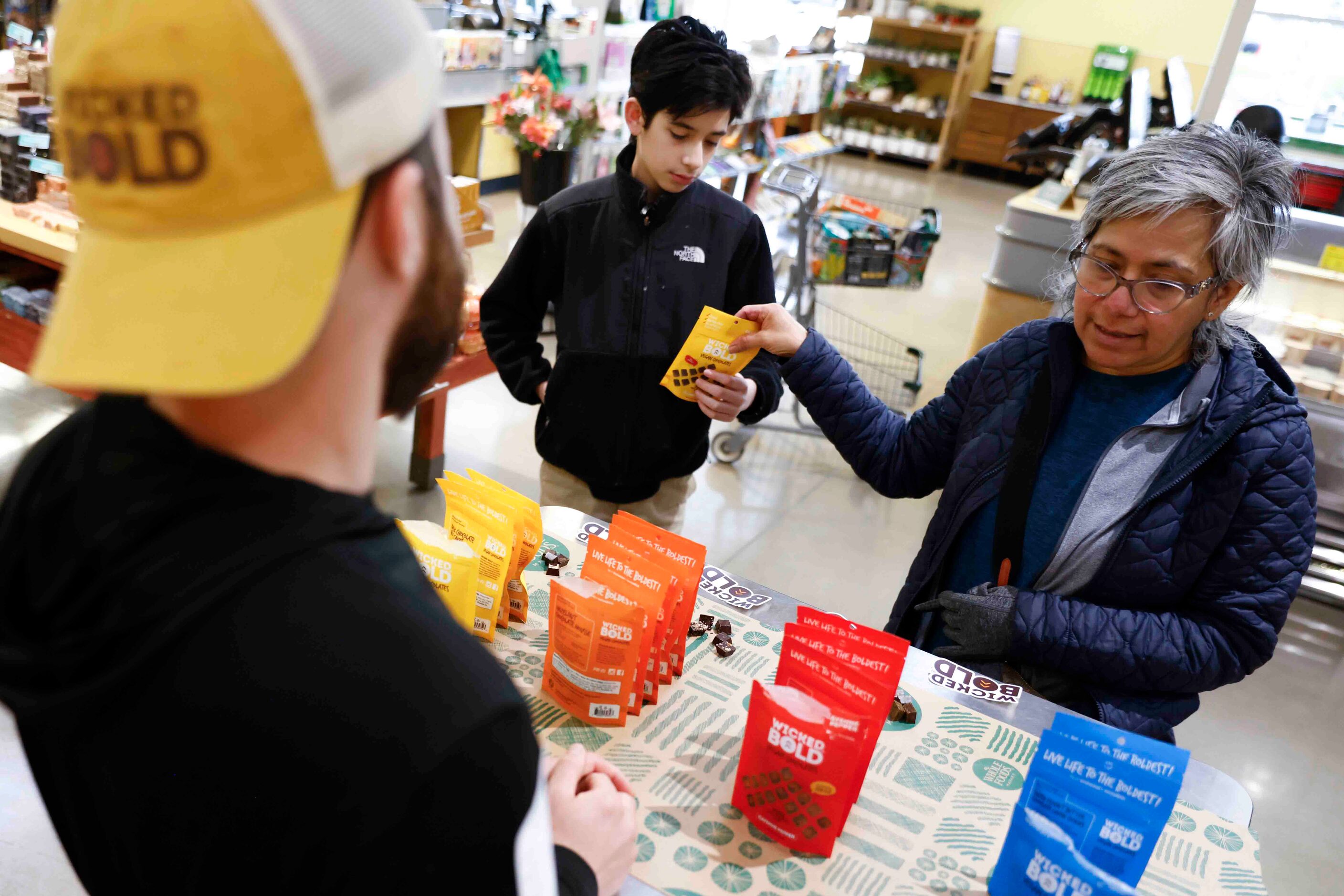 Deric Cahill (left) talks to Vangie Farmer (right) of Dallas as she hands over a pack of...