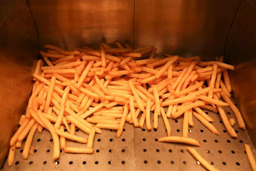 French fries sit in a container after frying in the kitchen of McDonald's Corp.'s 505th...
