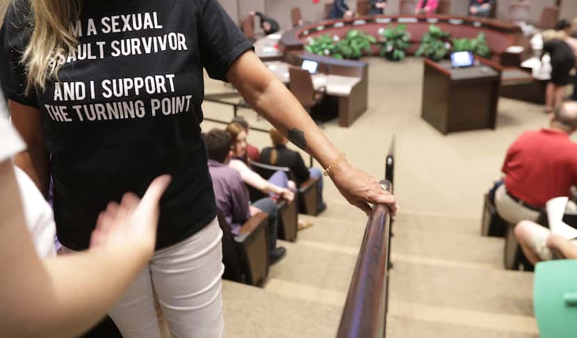 A person wearing a t-shirt saying "I am a sexual assault survivor" waits to speaks in...