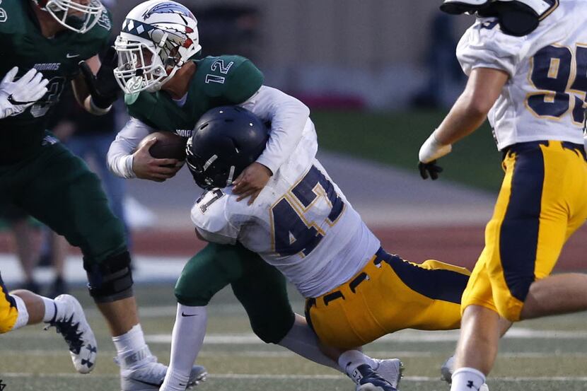 Waxahachie quarterback Bryce Salik is tackled by Highland Park defensive player John House...