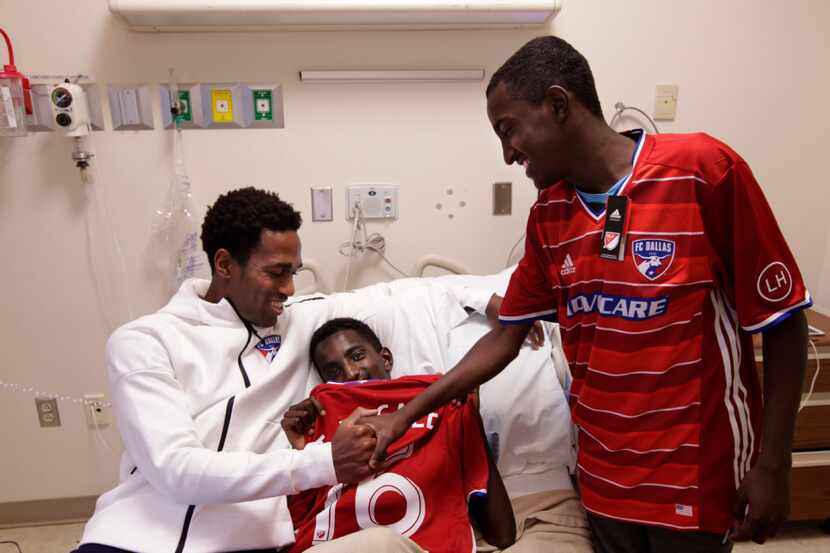 FC Dallas player Atiba Harris (left) visits with 16-year-old Tamirat Bogale and Tamirat's...
