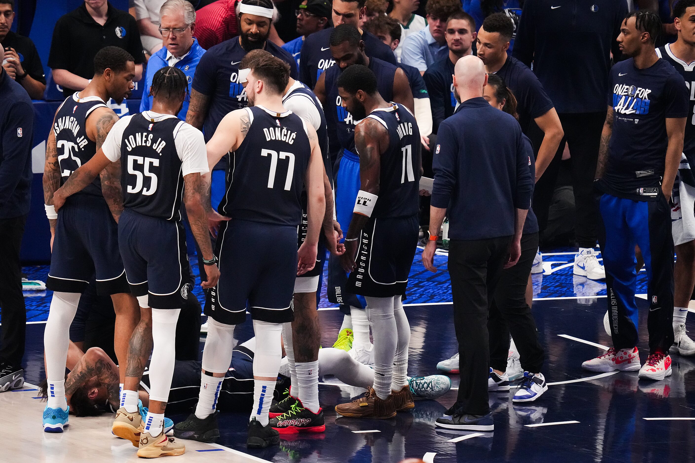 Dallas Mavericks players gather around center Dereck Lively II after he was injured during...