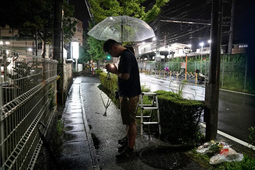 A couple prays after placing flowers near the Kyoto Animation building, Friday, July 18,...