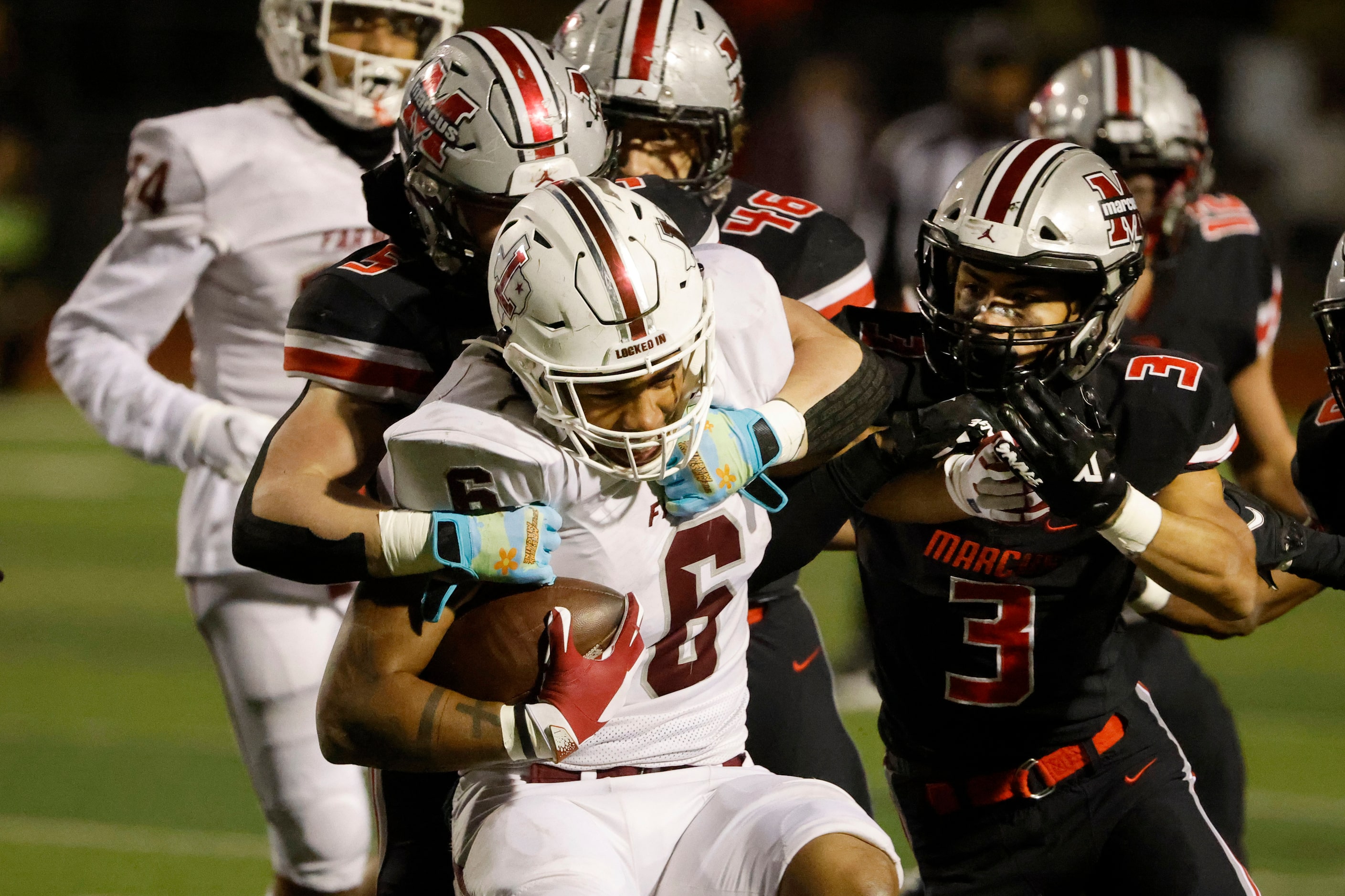 Flower Mound Marcus defenders Emmerick Dopona (5) and Chance Sautter (3) tackle Lewisville...