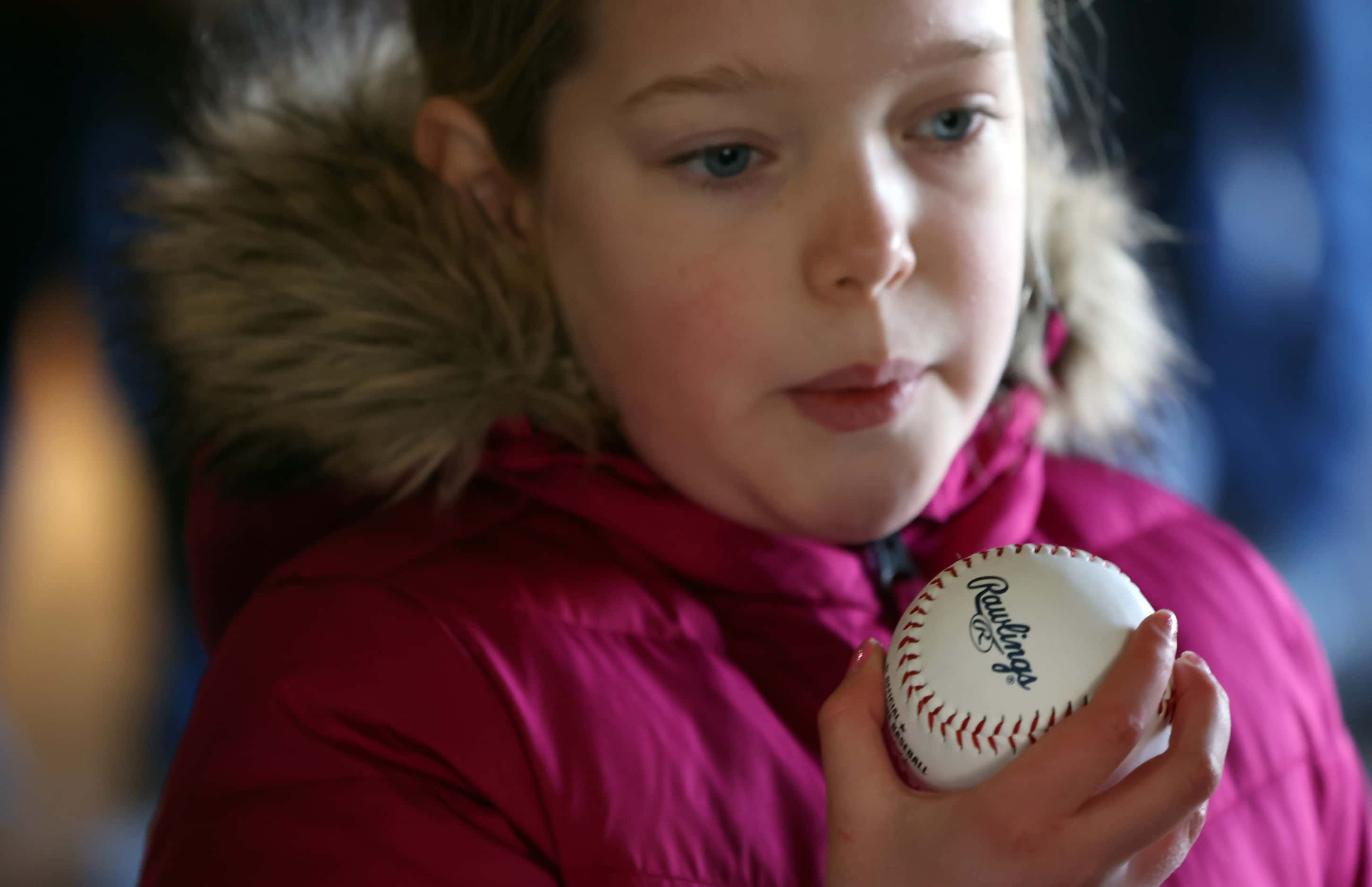 Texas Rangers fan Alexandra Herrington, 10, of Dallas, blows on her baseball to dry the ink...