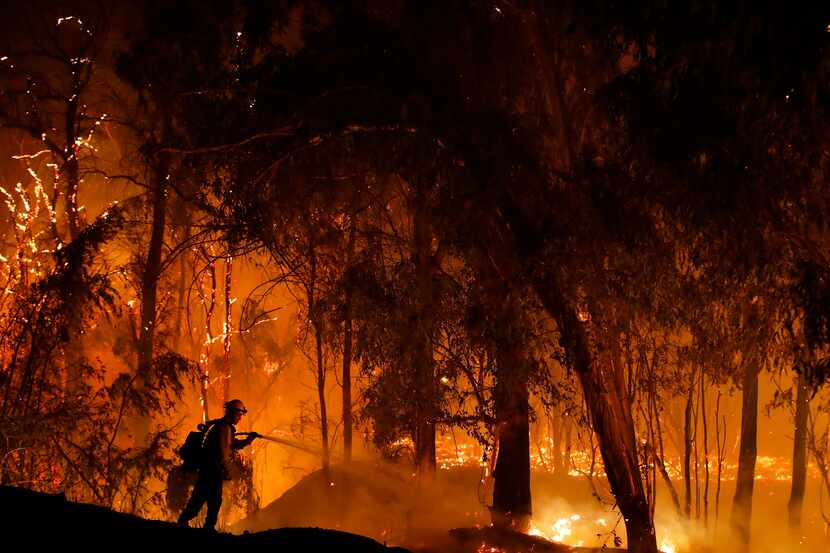 FILE - In this Oct. 31, 2019, file photo, a firefighter battles a wildfire known as the...