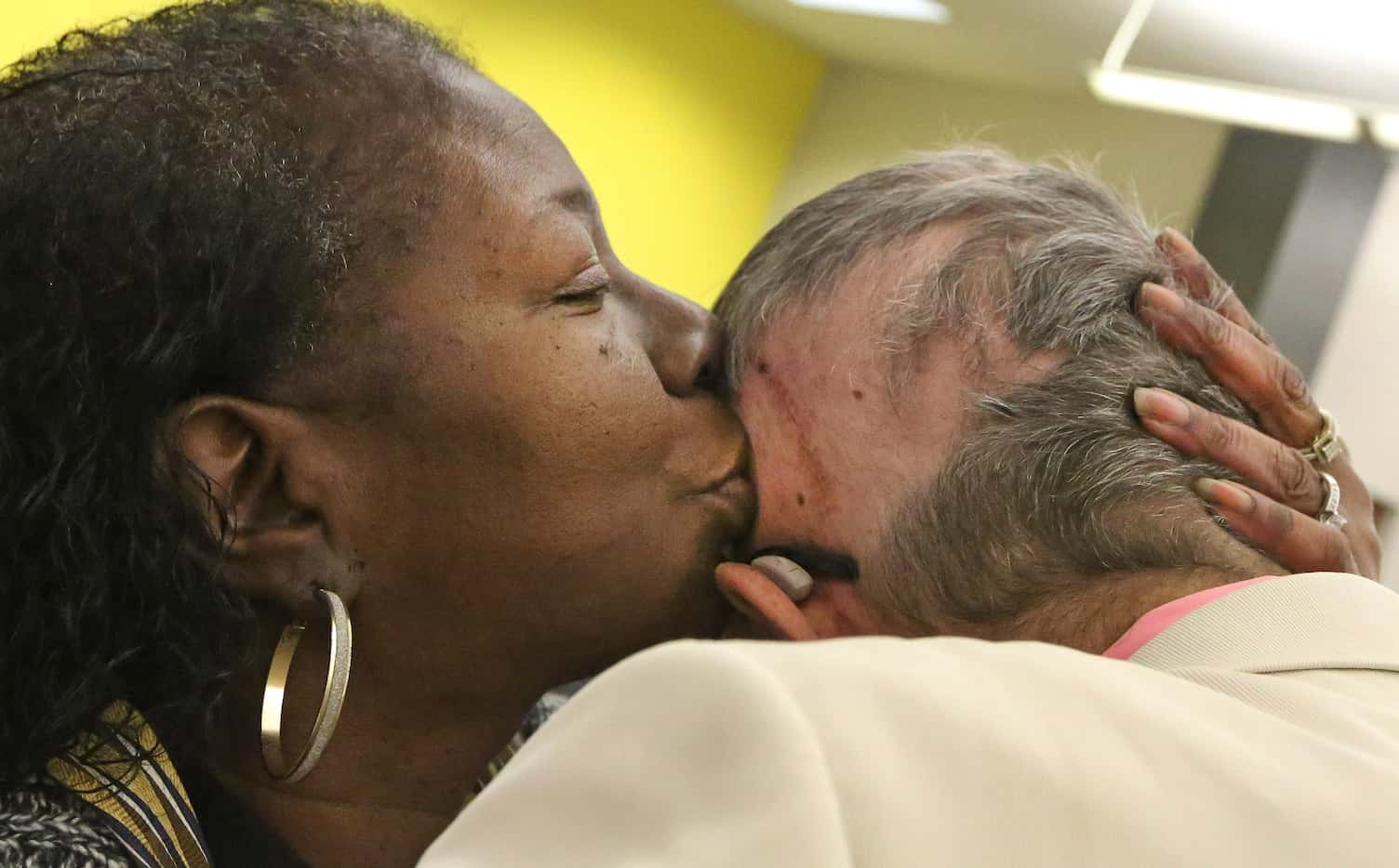 Co-worker Carol Caraway kisses the head of Jeffrey Weiss on the spot where his tumor was...