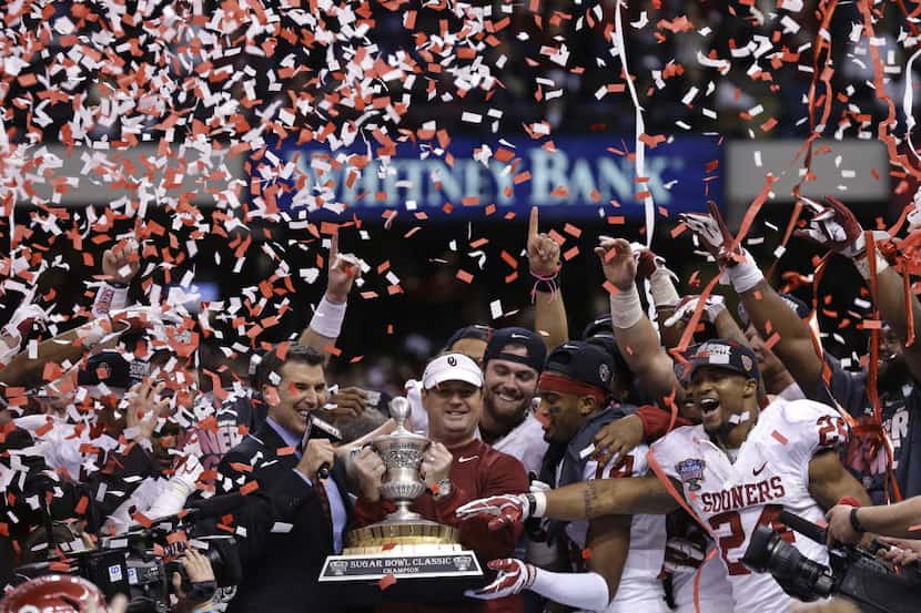 Oklahoma head coach Bob Stoops holds the Sugar Bowl trophy with his team after defeating...