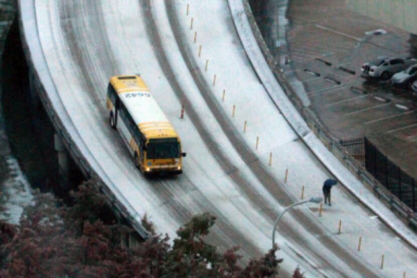 A DART bus and a couple of pedestrians made their way down the ice-covered Jefferson...
