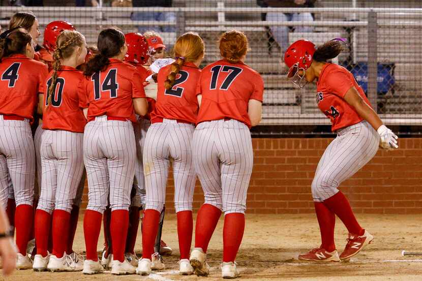 Marcus third baseman Tori Edwards (right) is greeted by her teammates after hitting a home...