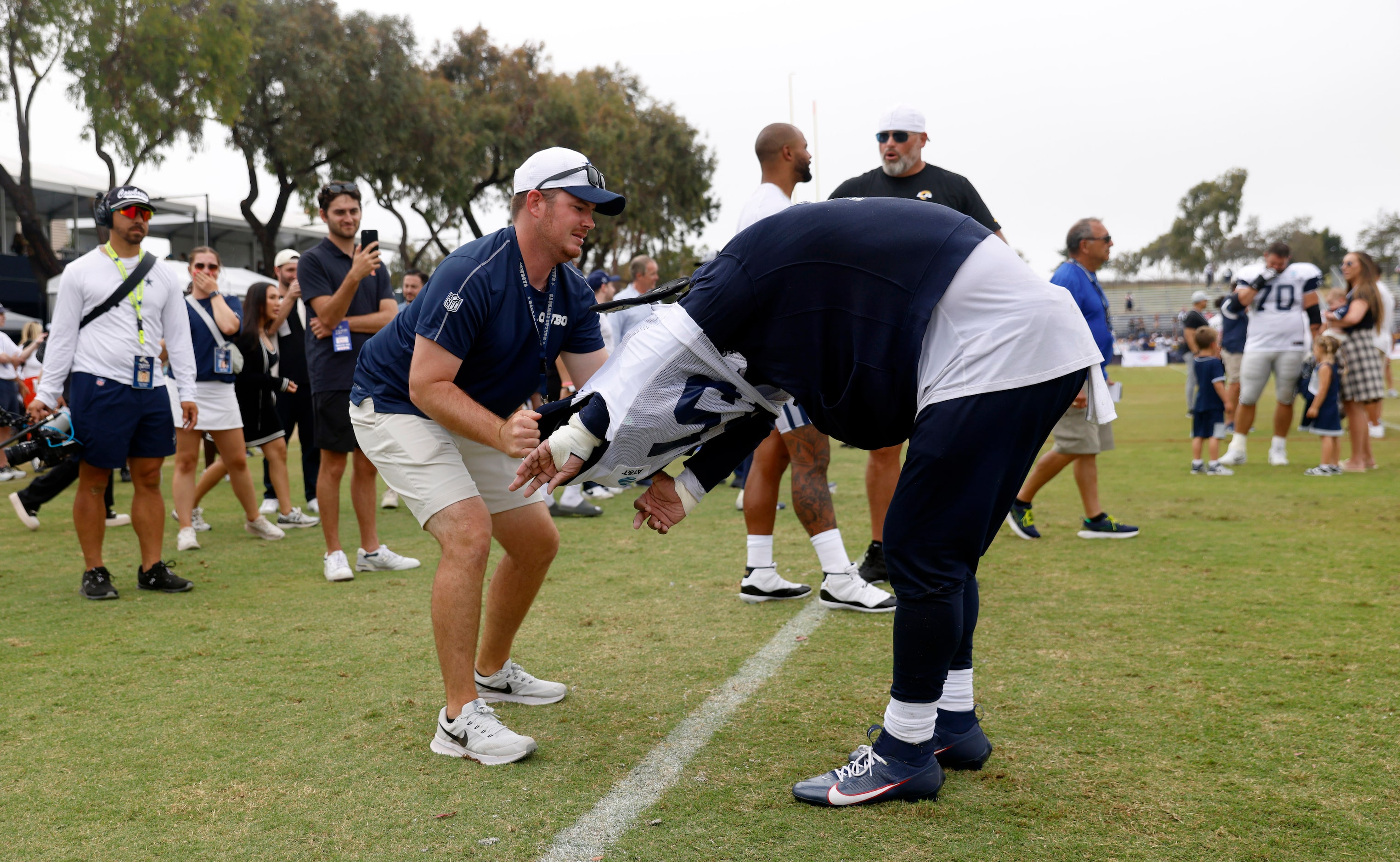 Public Relations Coordinator Bronte Hermesmeyer helps Dallas Cowboys running back Ezekiel...