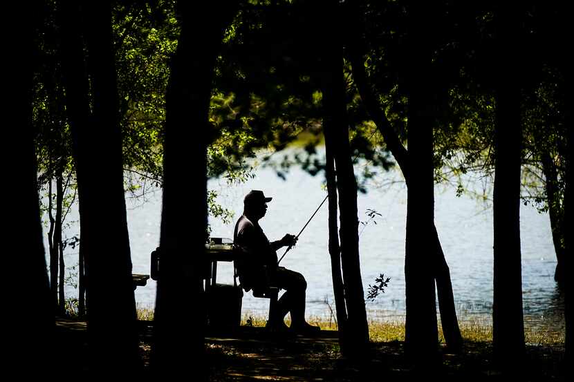 Rudy Sanchez of Dallas sat in the shade to work on his gear while fishing at Lake Tawakoni...