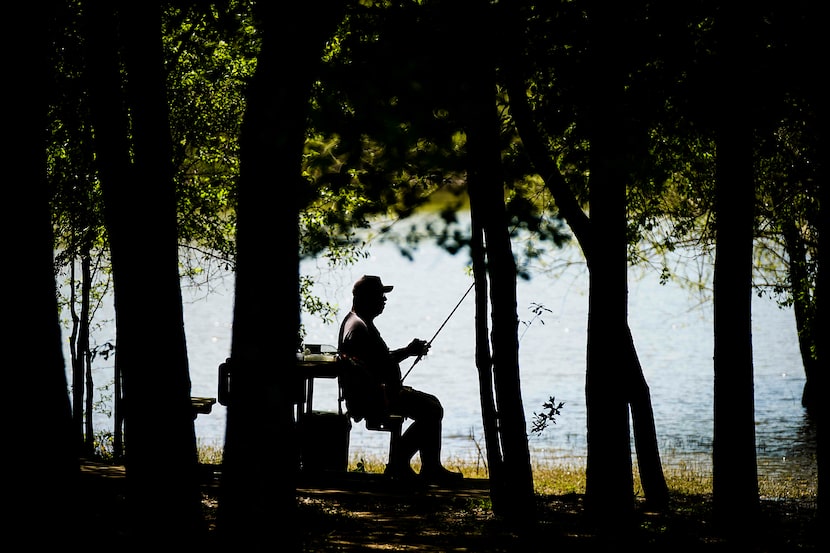 Rudy Sanchez of Dallas sat in the shade to work on his gear while fishing at Lake Tawakoni...