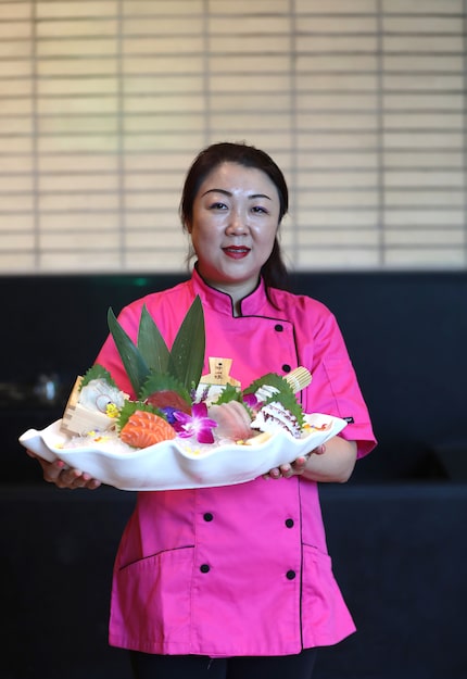 Chef Fawn Zhao holds a platter of sashimi at Feng Shui, a new restaurant in Dallas.