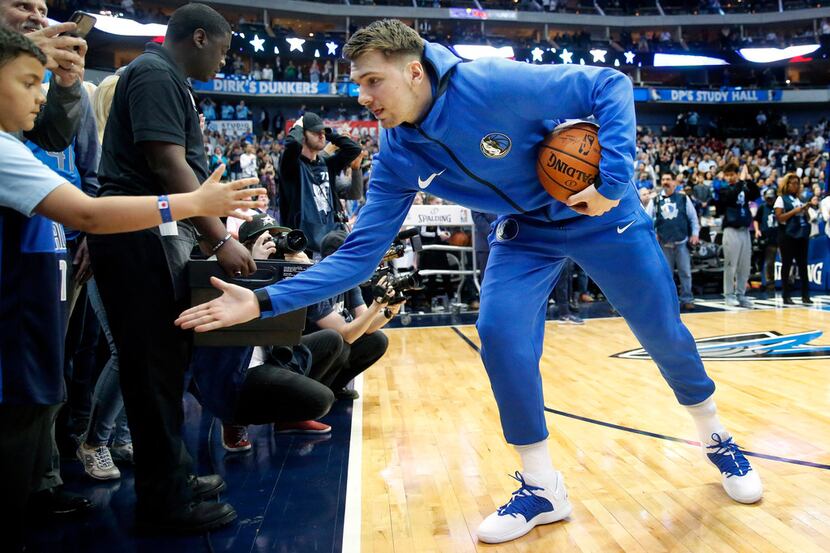 Dallas Mavericks forward Luka Doncic slaps hands with a young fan before his game against...