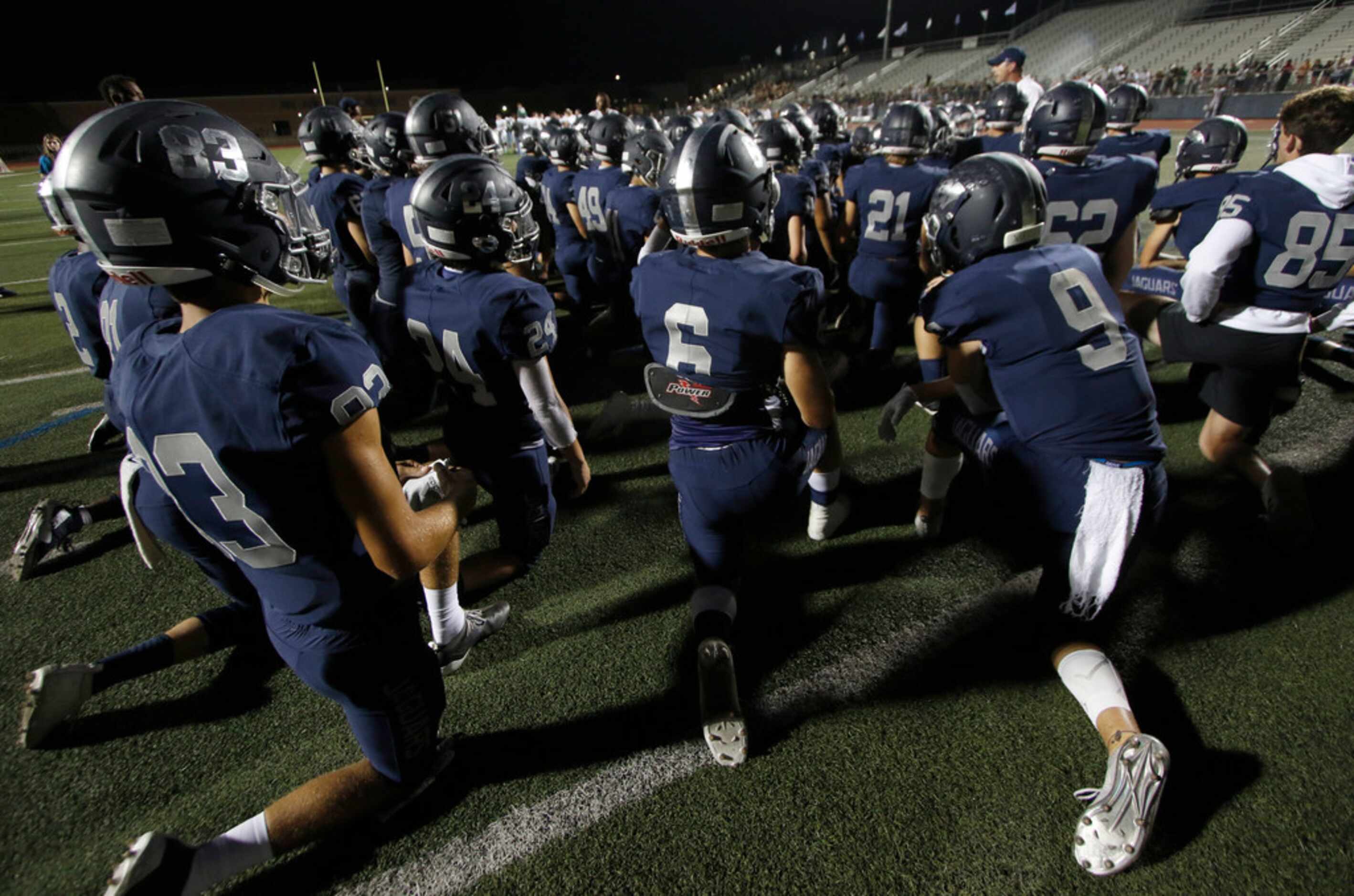 Carson Winters (9) takes a knee with teammates for words of encouragement from the coaching...