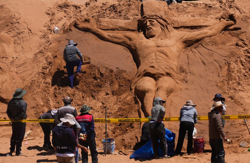 Bolivia: Un artista trabaja en una escultura de arena que muestra a Jesucristo en la cruz,...