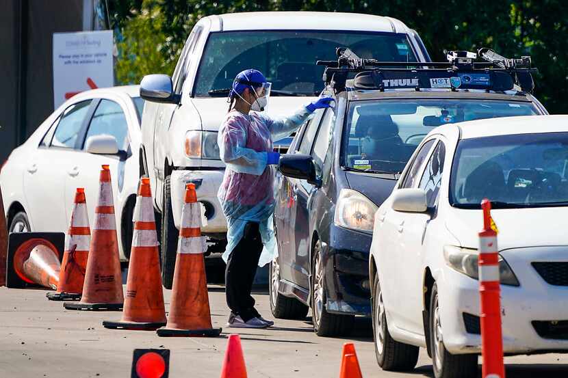 A health care worker interacted with motorists at a drive through COVID-19 testing facility...