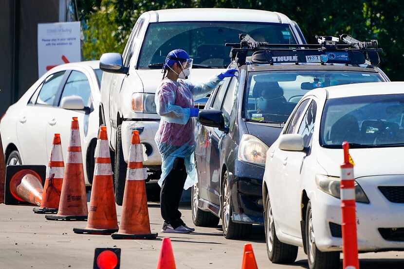 A health care worker interacts with motorists at a drive through COVID-19 testing facility...