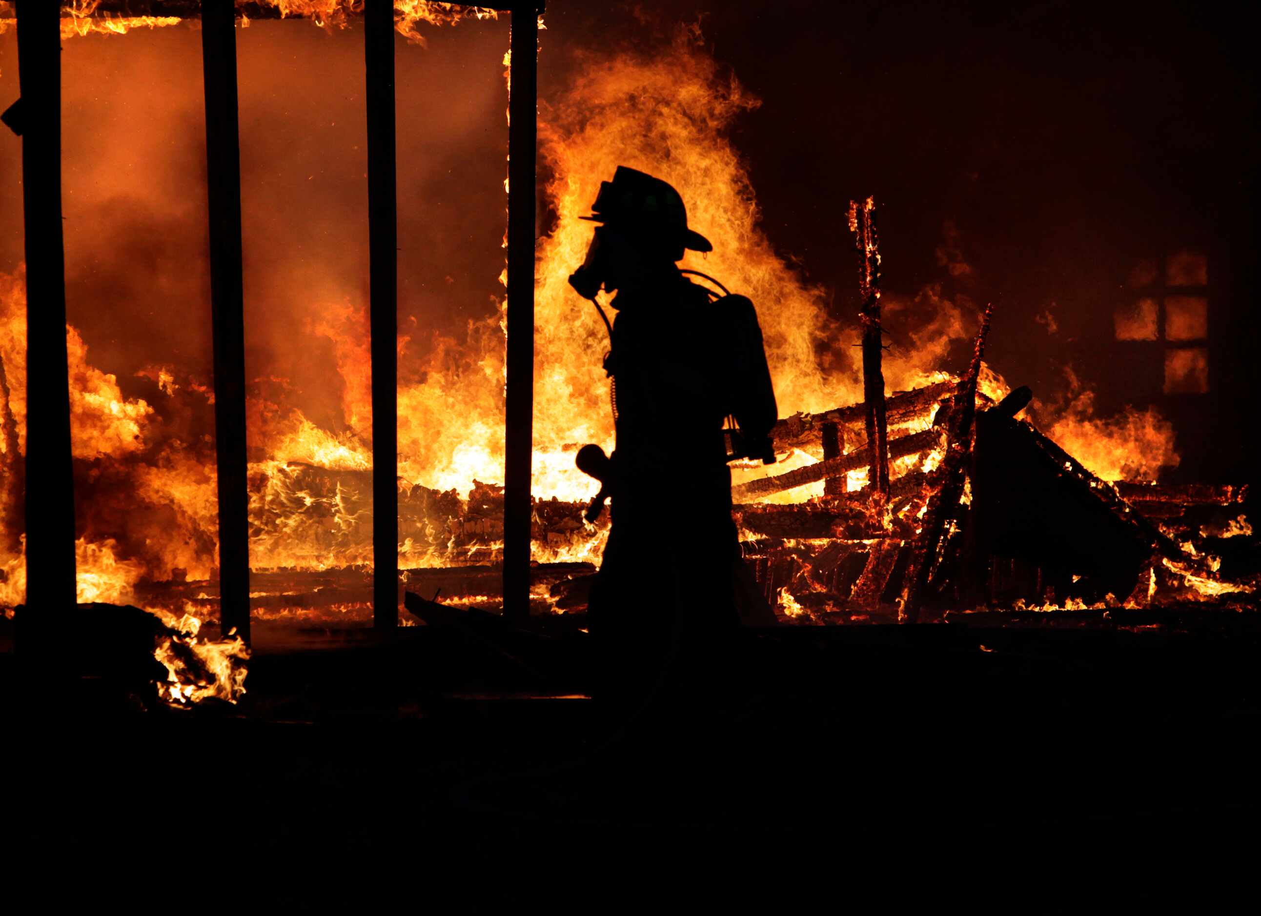 Intense flames silhouetted a Ferris firefighter before sunrise as he waited for water at Old...