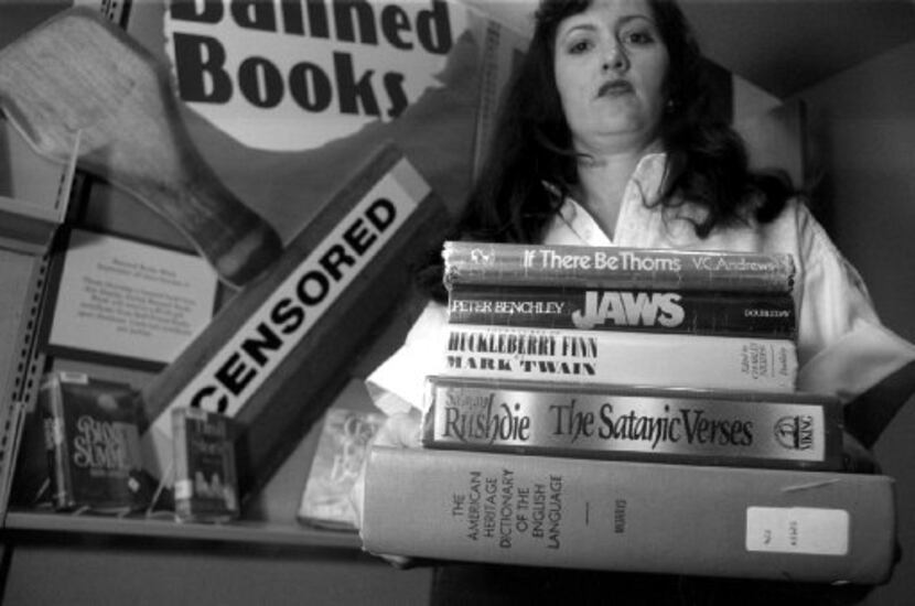Melissa King Odle holds a stack of books as part of a the "Banned Books" display in the...