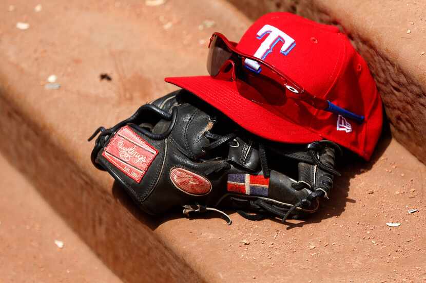 Texas Rangers hat, glove and sunglasses sit on the dugout steps in the third inning at Globe...