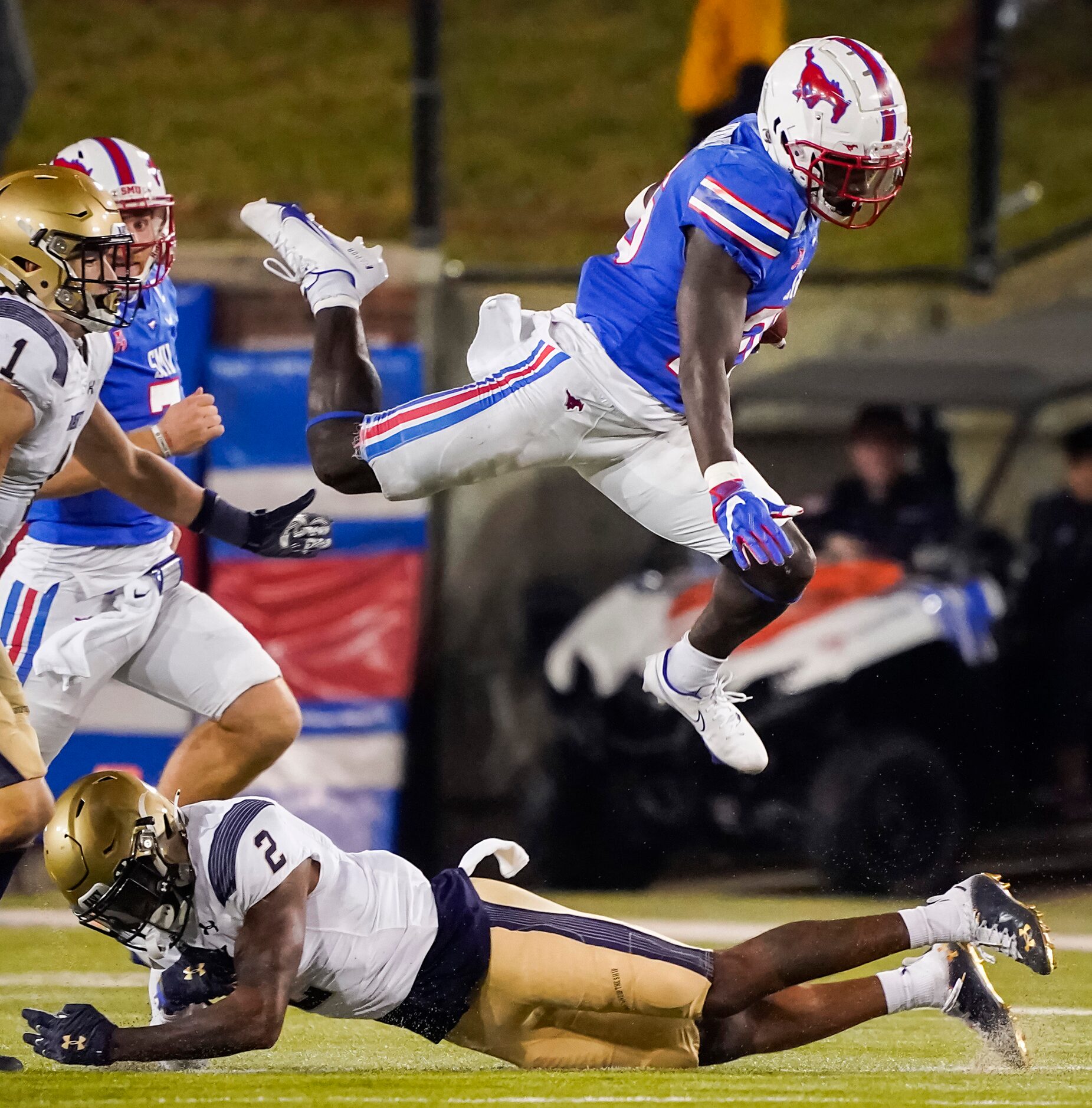 SMU running back Ulysses Bentley IV (26) hurdles Navy cornerback Marcus Wiggins (2) during...