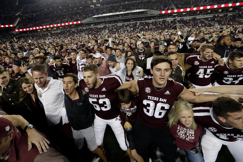 Students and fans join Texas A&M football players on the field after an NCAA college...