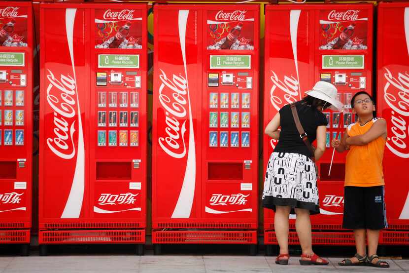 In this file photo, a woman and boy stand near Coca-Cola vending machines on the Olympic...