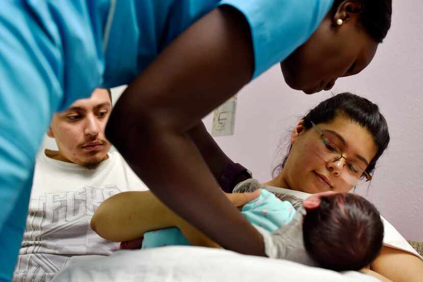 Gisma Gbib, left, a lactation consultant, helps Stefany Moreno, 21, breast feed her...