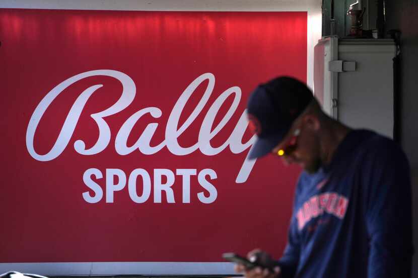 A member of the Houston Astros stands in the dugout in front of a Bally Sports sign before...