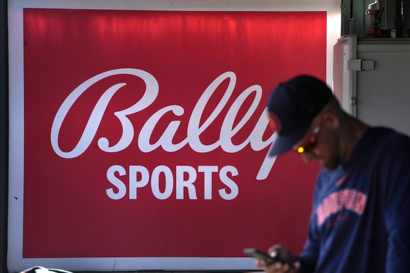 A member of the Houston Astros stands in the dugout in front of a Bally Sports sign before...